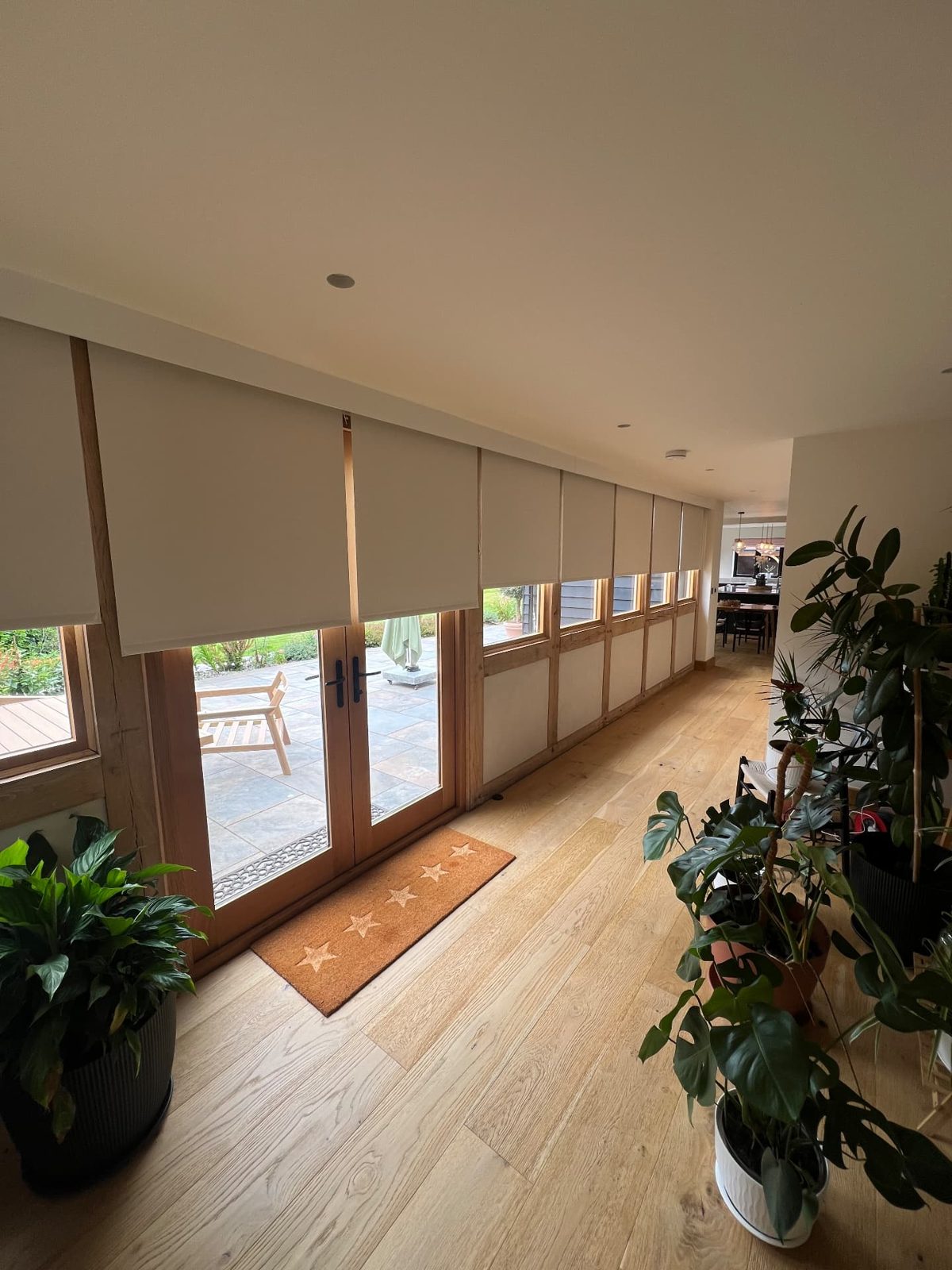 Row of neutral roller blinds partially lowered along a long hallway of windows