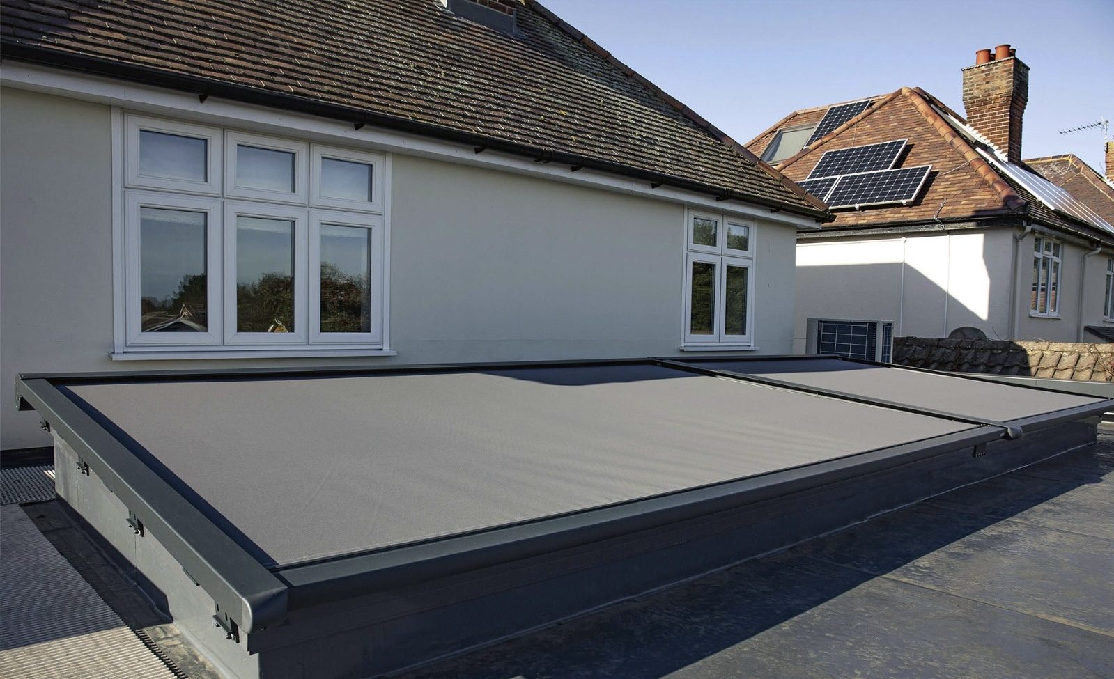 Retractable exterior fabric screen covering a large flat rooflight
