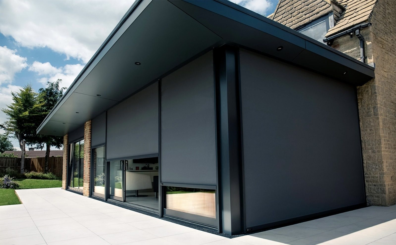 Dark grey solar shading zip screens integrated into the facade of a modern extension